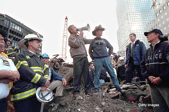 WASHINGTON, DC - SEPTEMBER 14: U.S. President George W. Bush speaks to rescue workers, firefighters and police officers from the rubble of Ground Zero September 14, 2001 in New York City. Standing with Bush is retired firefighter Bob Beckwith and at (R) is New York Governor George Pataki. (Photo by Eric Draper/White House/Getty Images)