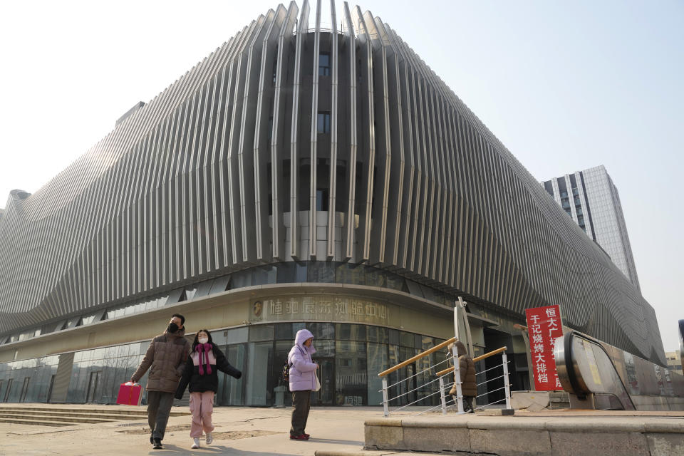 Residents walk past a Evergrande commercial complex with a shuttered Evergrande auto showroom in Beijing, Monday, Jan. 29, 2024. Chinese property developer China Evergrande Group on Monday was ordered to liquidate by a Hong Kong court, after the firm was unable to reach a restructuring deal with creditors. (AP Photo/Ng Han Guan)