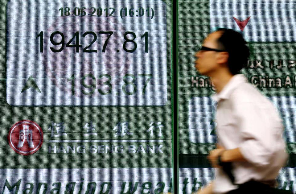 A man walks past a screen displaying stock index outside a local bank in Hong Kong Monday, June 18, 2012. Asian stock markets were up sharply Monday after elections in Greece eased fears of global financial turmoil, but analysts warned that the economic crisis shaking the 17 nations that use the euro was far from over. (AP Photo/Vincent Yu)