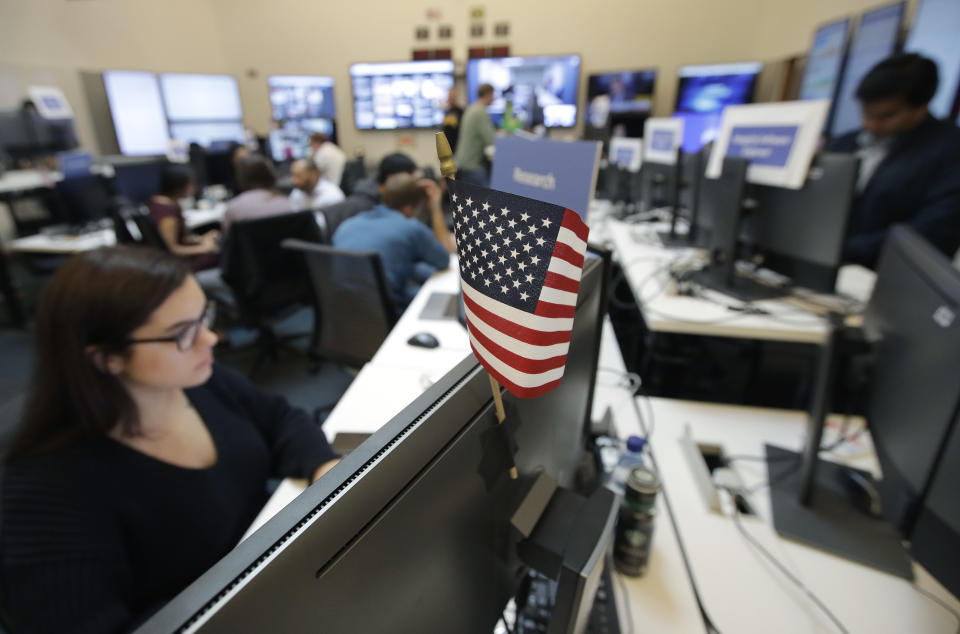 A flag of the United State is shown between monitors as workers sit at their desks during a demonstration in the war room, where Facebook monitors election related content on the platform, in Menlo Park, Calif., Wednesday, Oct. 17, 2018. (AP Photo/Jeff Chiu)