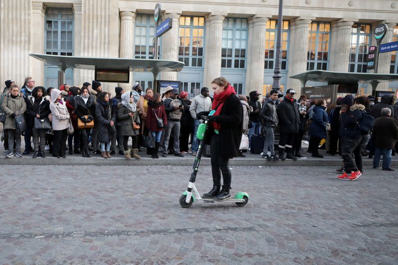 FILE PHOTO: A woman rides a scooter outside Gare du Nord station during strikes in Paris