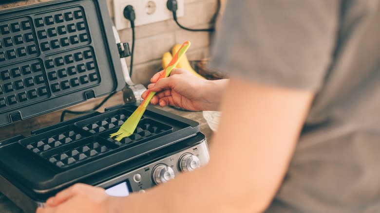 Person greasing a waffle iron