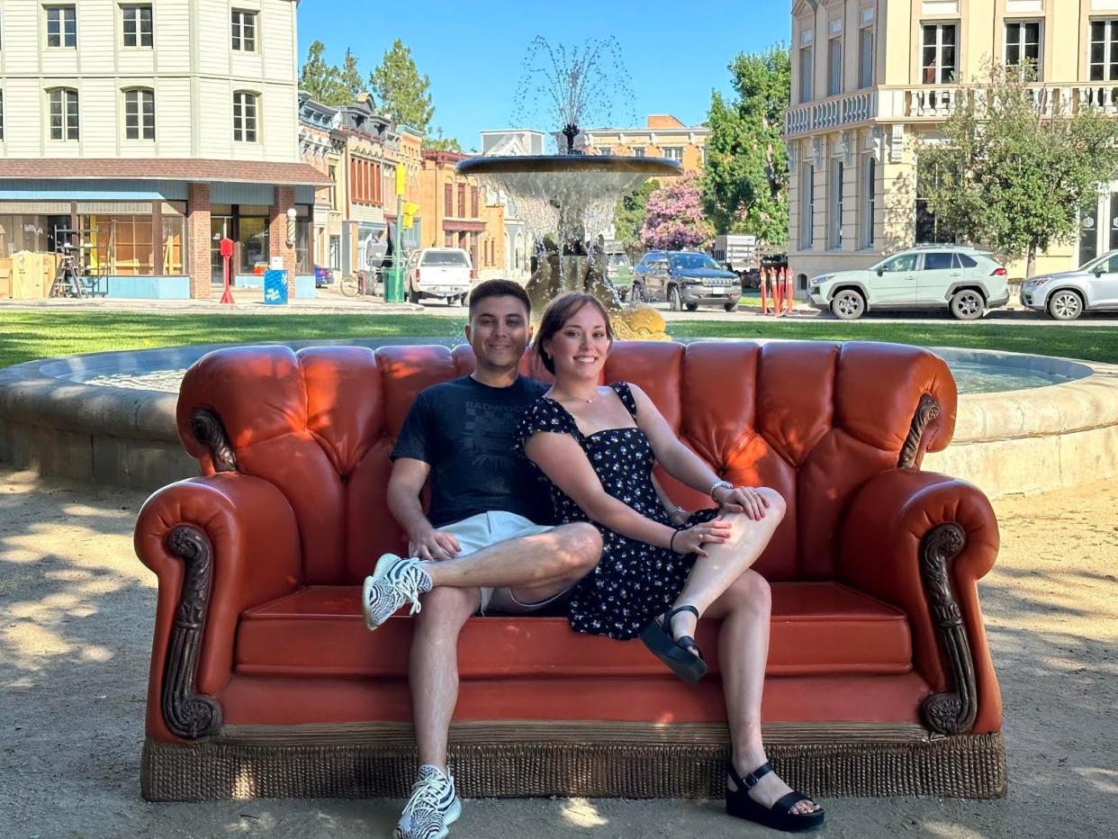 a couple sits on a couch outside