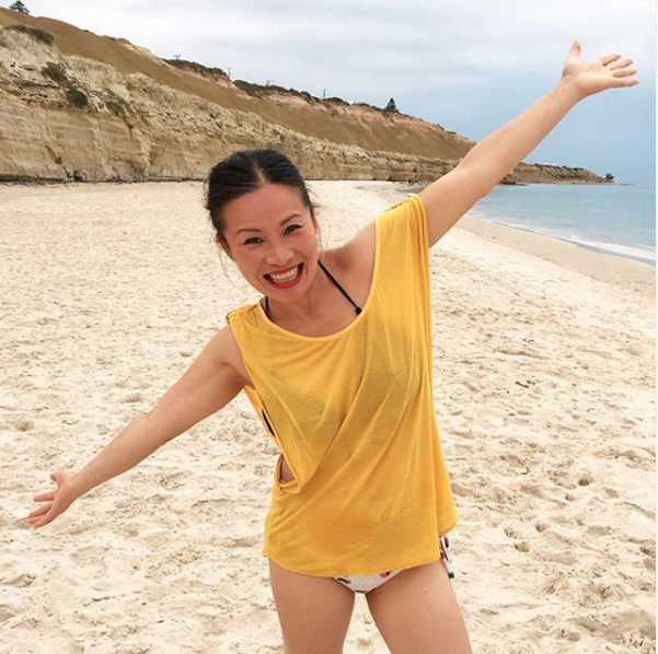 Poh Ling Yeow on the beach in a yellow t-shirt and bikini