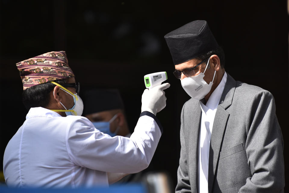 A Nepalese Health personnel in protective gear check the body temperature of Speaker of the House of Representatives, Agni Prasad Sapkota using thermal gun during the announcement of the new government's budget for the fiscal year 2020/2021 at Federal Parliament, Kathmandu, Nepal on Thursday, May 28, 2020.  (Photo by Narayan Maharjan/NurPhoto via Getty Images)