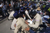 Local security personnel try to grab a banner from supporters of the Cambodia National Rescue Party in front of the the Phnom Penh Municipal Court in Phnom Penh, Cambodia, Tuesday, June 14, 2022. A Cambodian American lawyer and dozens of members of the now-dissolved opposition party were convicted of treason Tuesday in a trial that was the latest move to tame all opposition to the long-running rule of Prime Minister Hun Sen. (AP Photo/Heng Sinith)