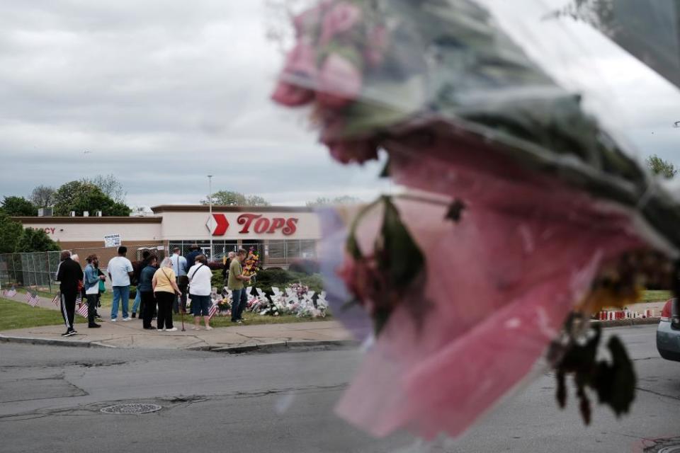 People gather at a memorial for the shooting victims outside of Tops grocery store.