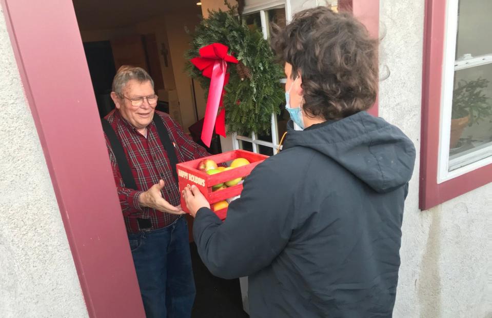 Former Stockbridge Valley Central School agriculture teacher Ray Lighthall, left, receives a basket of fruit and cookies from SVCS student Robby Wagner Dec. 21 at Lighthall's Munnsville home.