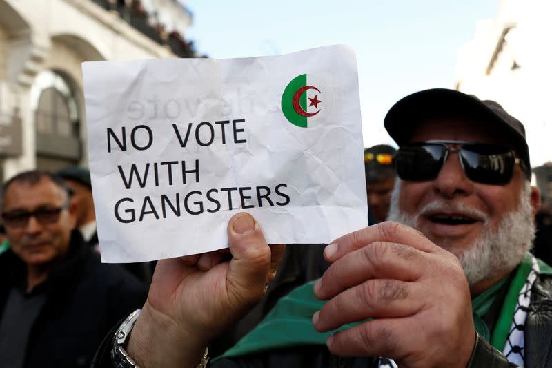 A demonstrator holds a sign as people take part in a protest to demand for the presidential election scheduled for next week to be cancelled, in Algiers