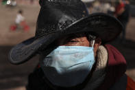 Hernaldo Gutierrez, wearing a protective face mask, waits in line to receive free fruits and vegetables from produce vendors who are donating their time and products to those facing hardship because of lost income due to the new coronavirus pandemic, in Quillicura, on the outskirts of Santiago, Chile, Wednesday, April 29, 2020. (AP Photo/Esteban Felix)