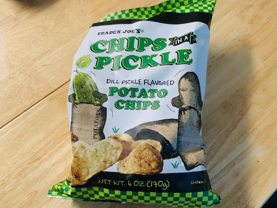 trader joe's pickle chips in the original white and green bag against a light wood table