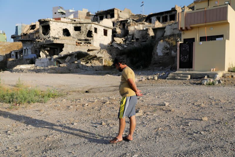 Luay Shaker stands over the remnants of his destroyed house in the old city of Mosul