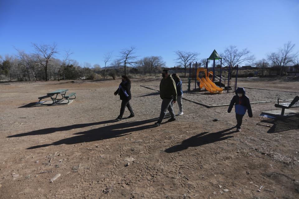 Angelica Rodriguez walks her U.S. citizen children; aged 13, 15 and 6, from a playground to their home on Wednesday, Dec. 23, 2020, in Santa Fe, N.M. Rodriguez and her husband, both cooks, struggled to pay rent this year as their hours were cut in half. As immigrants in the country without legal permission, they're ineligible for state unemployment or federal stimulus money. (AP Photo/Cedar Attanasio)