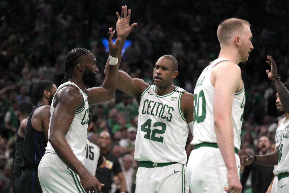 Boston Celtics guard Jaylen Brown, left, celebrates with center Al Horford, center, as the Celtics lead the Dallas Mavericks during the second half of Game 1 of the NBA Basketball Finals against the Dallas Mavericks, Thursday, June 6, 2024, in Boston. (AP Photo/Charles Krupa)