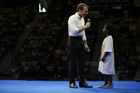 Emmanuel Macron, head of the political movement En Marche ! (Onwards !) and 2017 presidential candidate of the French centre-right speaks with a young boy at a meeting at Saint Denis as he campaigns on the French Indian Ocean island of the Reunion, March 25, 2017. REUTERS/Laurent Capmas