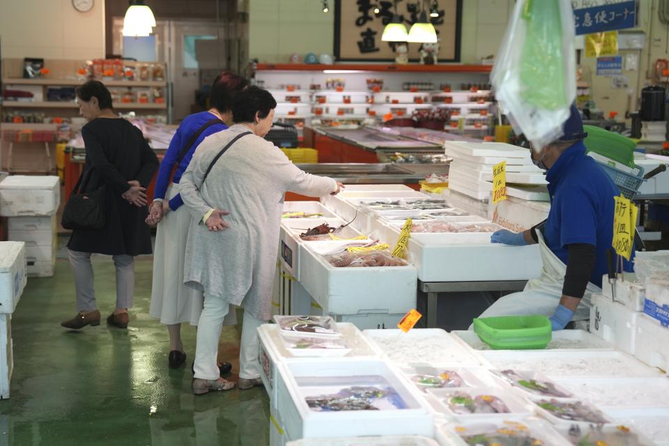 Visitors check seafood sold at the seafood market "Lalamew" near the Onahama fish port in Iwaki City, Fukushima Prefecture, on Oct. 19, 2023 in Iwaki, northeastern Japan. Fishing communities in Fukushima feared devastating damage to their businesses from the tsunami-wrecked nuclear power plant’s ongoing discharge of treated radioactive wastewater into the sea. Instead, they're seeing increased consumer support as people eat more fish, a movement in part helped by China’s ban on Japanese seafood. (AP Photo/Eugene Hoshiko)