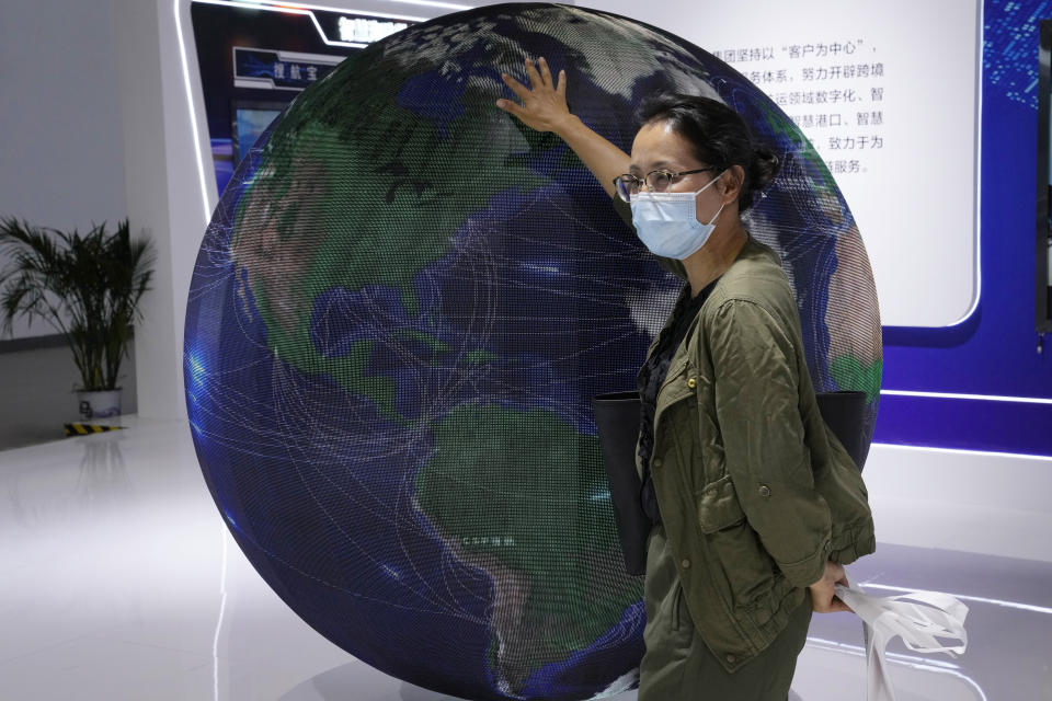 A visitor to a trade show places her hand on a globe in Beijing, China, Tuesday, Sept. 7, 2021. Companies in China would need government approval to transfer important data abroad under proposed rules announced Friday that would tighten Beijing's control over information and might disrupt operations for international corporations. (AP Photo/Ng Han Guan)