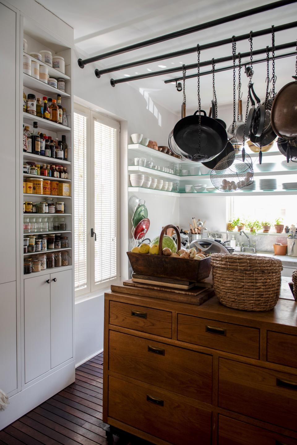 Every facet of the couple’s kitchen was crafted by a local carpenter. The cabinets are painted in white oil and the chest of drawers is made of pure oak; a mix of custom-designed rods and chains suspend various pots and pans in the air, making for easy access.