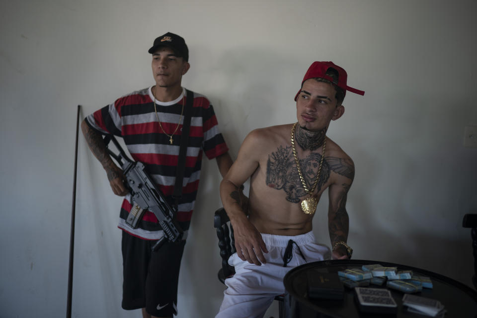 Trap artist Denilson, known as "TB" holds an Airsoft gun a he stands behind Wesley Souza "MC Branquinho" during the recording of a Trap de Cria music video in the Jardim Catarina community in Sao Gonçalo, Rio de Janeiro state, Brazil, Sunday, April 11, 2021. According to Vinicius Moraes, who is doing his doctoral research in social anthropology at the Federal University of Rio de Janeiro, Trap de Cria, also known as Homegrown Trap or Real Trap, has begun gaining traction beyond the favelas among the middle class. (AP Photo/Felipe Dana)