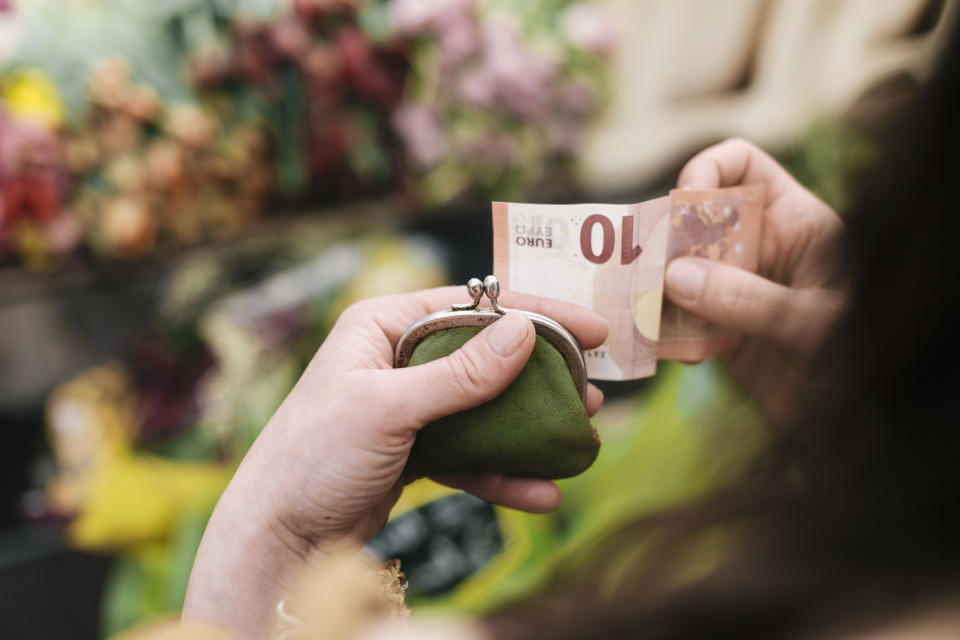 Close-up of woman paying for Flowers with a 10 Euro Bill at an outdoor Market.