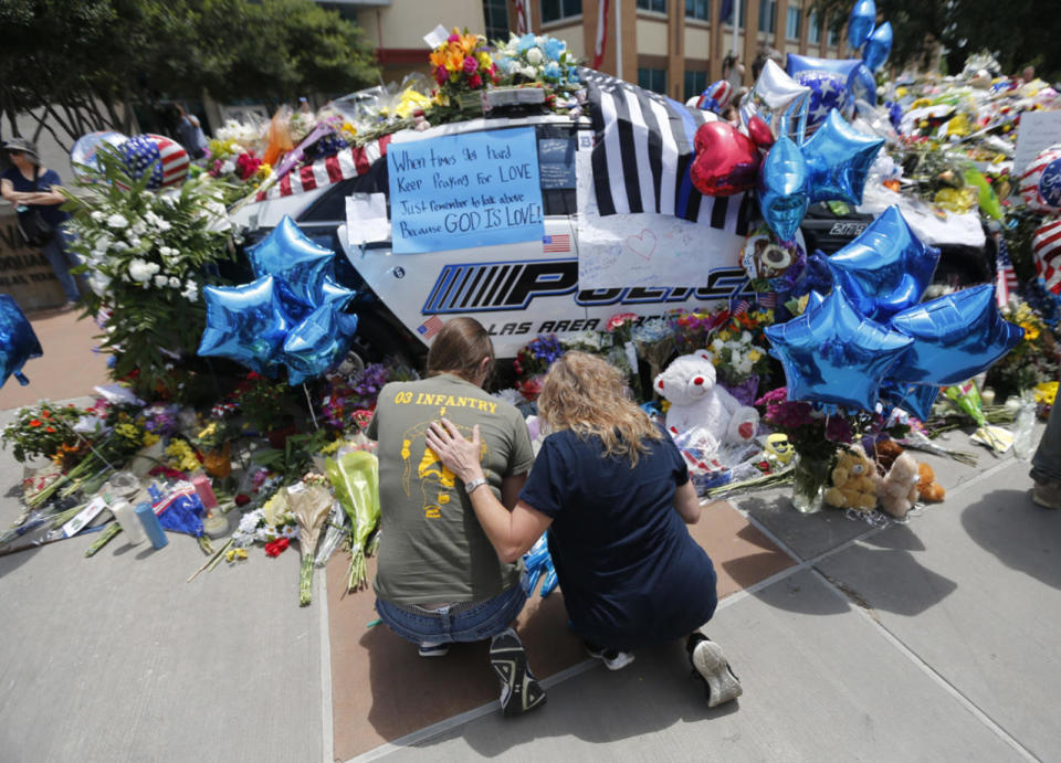 Cheryl Heard, right, and Tatia Edwards, pay their respects at a makeshift memorial of police cars,