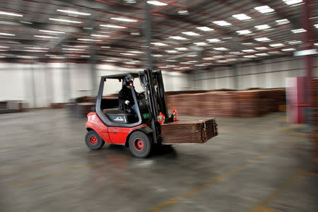 A worker loads copper cathodes into a warehouse near Yangshan Deep Water Port, south of Shanghai in this March 23, 2012 file photo. REUTERS/Carlos Barria/File Photo