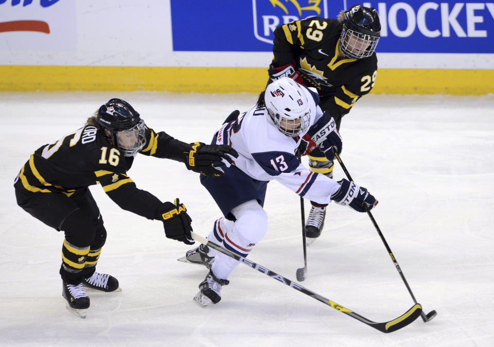 FILE - In this April 2, 2013, file photo, Canada's Jayna Hefford, left, and Marie-Philip Poulin attempt to stop United States' Julie Chu during the first period of a women's world ice hockey championship game in Ottawa, Ontario. Since women's ice hockey became an Olympic sport in Nagano in 1998, the Canada and the United States have dominated the podium, winning every gold medal and all but one of the silvers. (AP Photo/The Canadian Press, Seak Kilpatrick, File)(