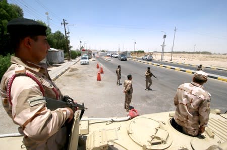 Iraqi soldiers stay guard at the entry of Zubair oilfield after a rocket struck the site of residential and operations headquarters of several oil companies in Basra