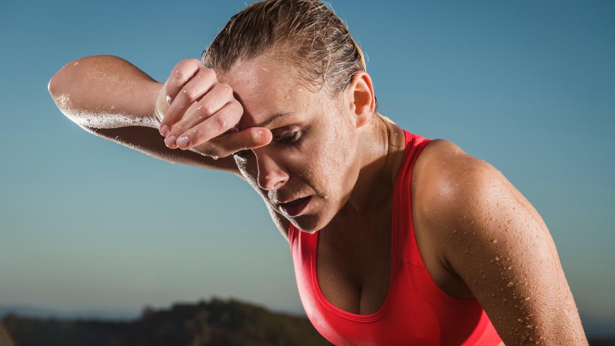  Woman wiping sweat from forehead. 