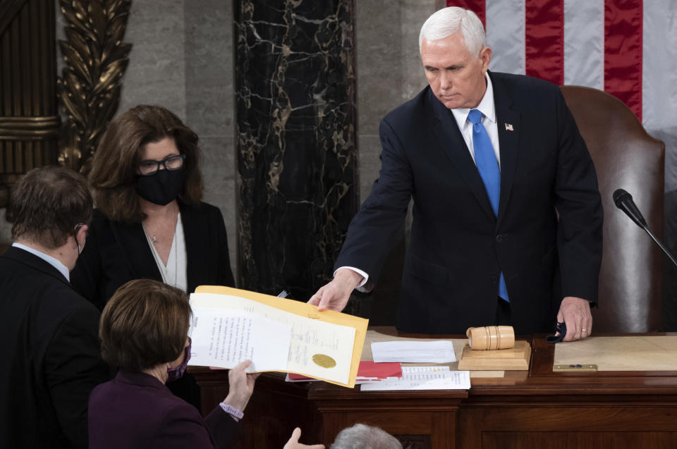 FILE - Vice President Mike Pence hands the electoral certificate from the state of Arizona to Sen. Amy Klobuchar, D-Minn., as he presides over a joint session of Congress as it convenes to count the Electoral College votes cast in November's election, at the Capitol in Washington, Wednesday, Jan. 6, 2021. (Saul Loeb/Pool via AP, File)