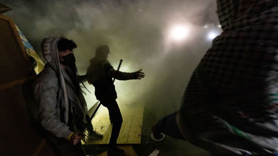 Pro-Palestinian demonstrators engulfed in tear gas regroup and rebuild the barricade surrounding the encampment set up on the campus of the University of California Los Angeles (UCLA) as clashes erupt with counter protesters, in Los Angeles on May 1, 2024. - ETIENNE LAURENT/AFP/AFP via Getty Images