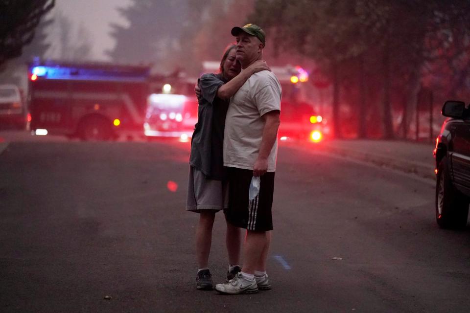 A couple comfort each other as firefighters battle a blaze (AP)