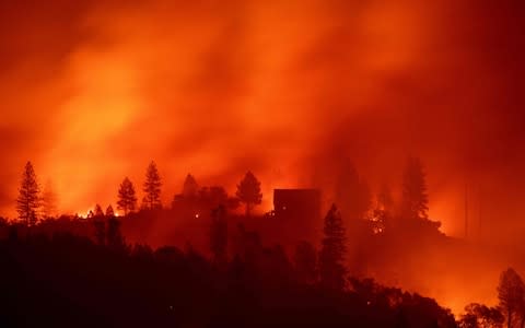 Flames from the Camp fire burn near a home atop a ridge near Big Bend, California - Credit: AFP