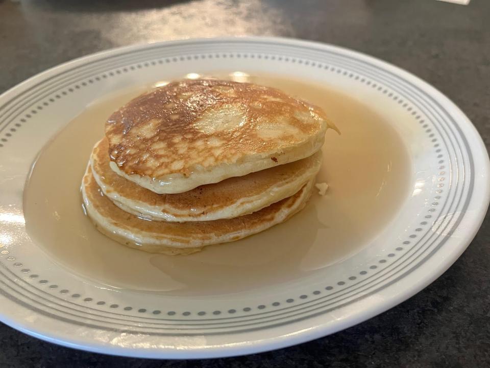 stack of three pancakes on a plate with syrup on top