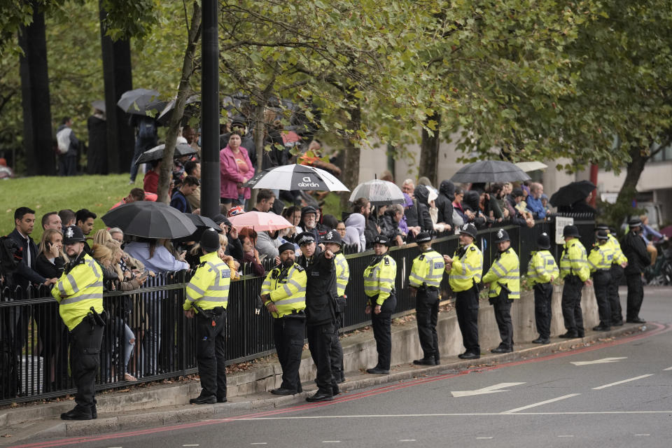 Police line up in front of people waiting for the convoy carrying the coffin of late Queen Elizabeth II, as it heads towards Buckingham Palace in London, Tuesday, Sept. 13, 2022. Britain's longest-reigning monarch who was a rock of stability across much of a turbulent century, died Thursday Sept. 8, 2022, after 70 years on the throne. She was 96. (AP Photo/Vadim Ghirda)