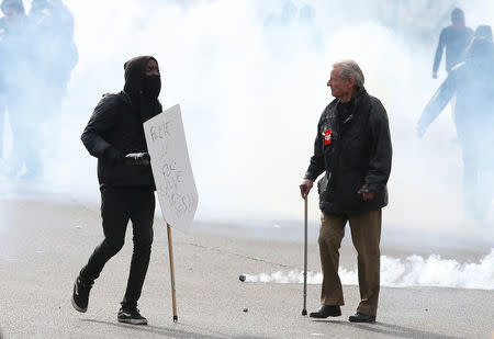 A masked youth and a demonstrator wearing a CGT badge walk through a cloud of tear gas during a demonstration against the French labour law proposal in Paris, France, as part of a nationwide labor reform protests and strikes, April 28, 2016. REUTERS/Charles Platiau