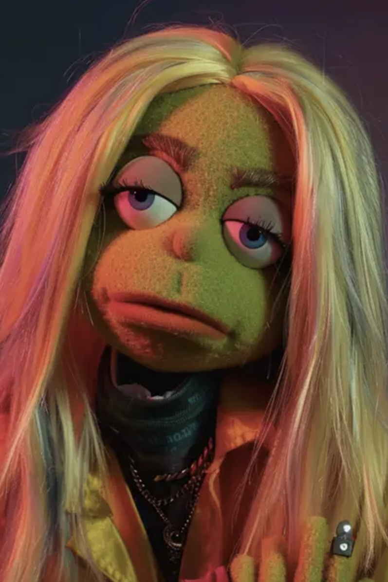 Puppet with blonde hair and expression of ennui, wearing a jacket and multiple necklaces