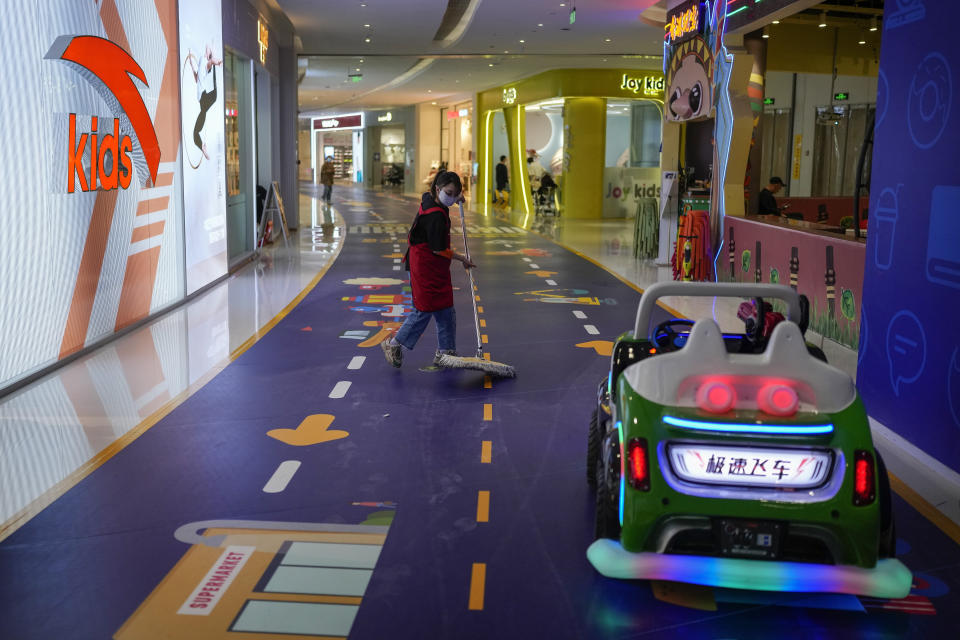 A worker wearing a face mask wipes near a toy car parked along the stores for children inside a shopping mall in Beijing, Tuesday, April 4, 2023. The Asian Development Bank says China's recovery from the pandemic and strong demand in India will drive strong economic growth in Asia this year. (AP Photo/Andy Wong)