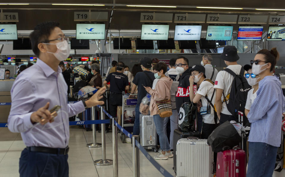 An airport official speaks to tourists from Wuhan, China, waiting for a charter flight back to Wuhan at the Suvarnabhumi airport, Bangkok, Thailand, Friday, Jan. 31, 2020. A group of Chinese tourists who have been trapped in Thailand since Wuhan was locked down due to an outbreak of new virus returned to China on Friday. (AP Photo/Gemunu Amarasinghe)