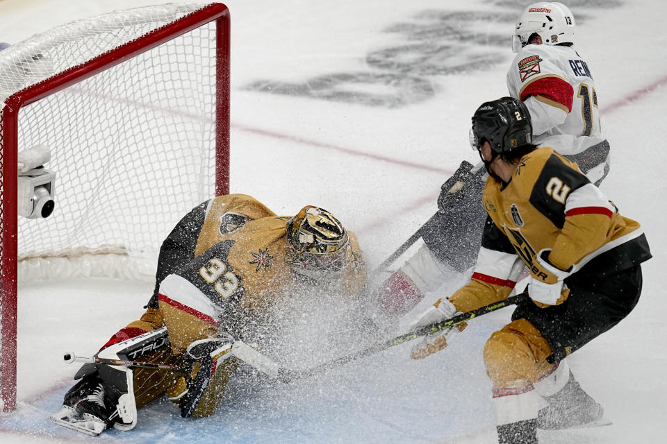 Vegas Golden Knights goaltender Adin Hill (33) stops a shot by Florida Panthers center Sam Reinhart, right, during the third period of Game 1 of the NHL hockey Stanley Cup Finals, Saturday, June 3, 2023, in Las Vegas. The Golden Knights defeated the Panthers 5-2. (AP Photo/Abbie Parr)