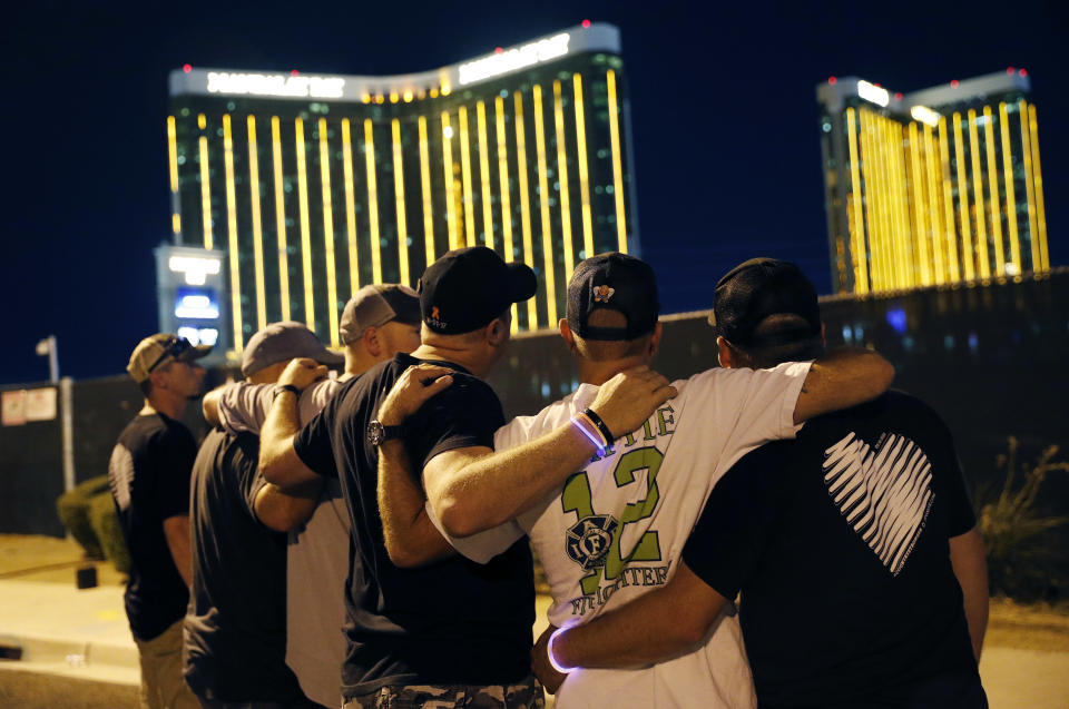 Survivors return to the scene of a mass shooting on the first anniversary, Monday, Oct. 1, 2018, in Las Vegas. Hundreds of survivors of the Las Vegas mass shooting have formed a human chain around the shuttered site of a country music festival where a gunman opened fire last year. (AP Photo/John Locher)