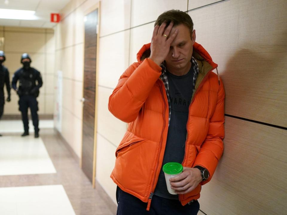 The Russian opposition leader Alexei Navalny holds his forehead in his hand.