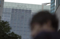 A man walk past the headquarters of Japanese advertising company Dentsu Inc. in Tokyo Wednesday, Jan. 23, 2019. One of Japan's most powerful companies, the giant agency Dentsu Inc. is part of an investigation into alleged vote-buying connected with landing the 2020 Olympics for Tokyo. (AP Photo/Eugene Hoshiko)