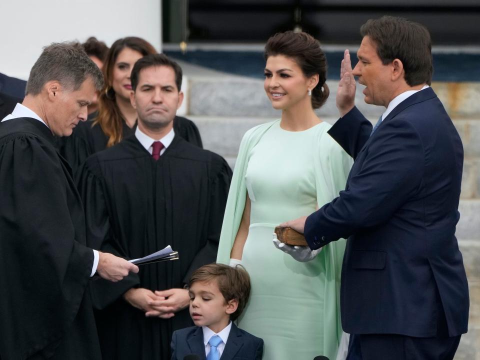 Florida Gov. Ron DeSantis, right, is sworn by Florida Supreme Court Chief Justice Carlos Muniz, left, to begin his second term during an inauguration ceremony outside the Old Capitol Tuesday, January 3, 2023, in Tallahassee, Florida. Looking on is DeSantis' wife Casey, second from right, and their son Mason.