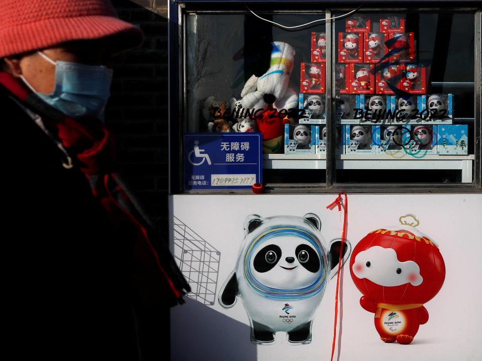 A woman walks past an image of the Beijing 2022 Winter Olympics Mascots at a souvenir store, at a hutong alley, in Beijing, China January 29, 2022.