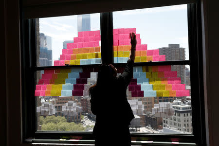 An employee creates a rainbow image on a window with Post-it notes at the Horizon Media offices at 75 Varick Street in lower Manhattan, New York, May 18, 2016. REUTERS/Mike Segar