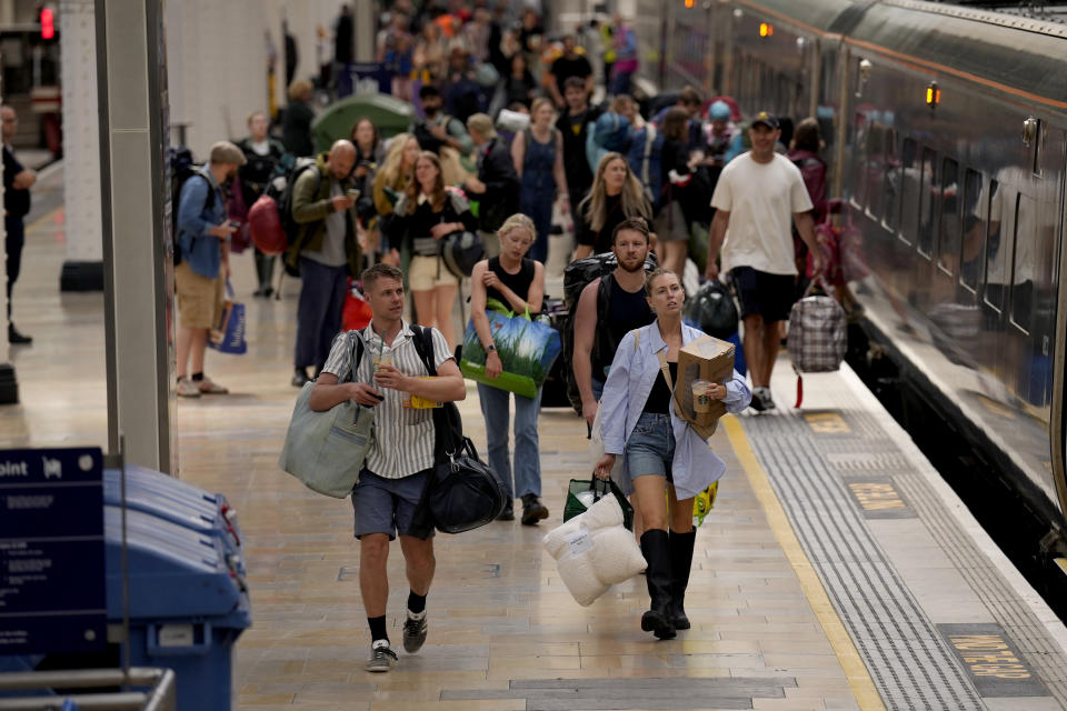 Passengers with camping equipment walk to board a train to go to the Glastonbury music festival at Paddington railway station, in London, during a railway workers strike, Thursday, June 23, 2022. Tens of thousands of railway workers walked off the job in Britain on Tuesday, bringing the train network to a crawl in the country's biggest transit strike for three decades. Britain faces the second of three national railway strikes Thursday after new negotiations between union and employers ended in deadlock. . (AP Photo/Matt Dunham)