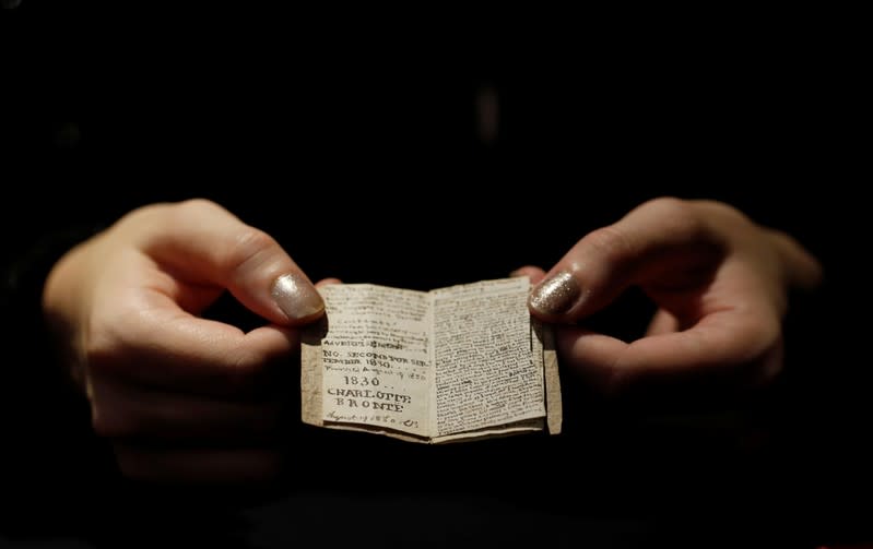 An employee displays the second issue of Young Men's Magazine, a miniature manuscript dated 1830, written by Charlotte Bronte when she was 14 years old, before being put on auction at Drouot auction house in Paris