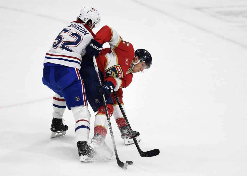 Florida Panthers center Eetu Luostarinen tries to control the puck in front of Montreal Canadiens defenseman Justin Barron (52) during the second period of an NHL hockey game Saturday, Dec. 30, 2023, in Sunrise, Fla. (AP Photo/Michael Laughlin)