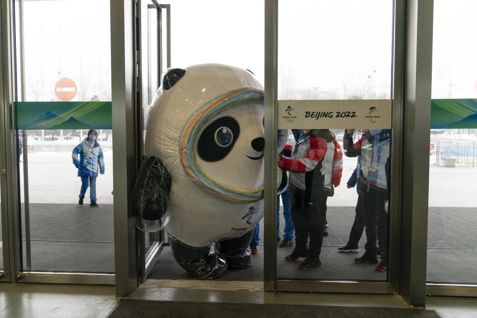 FILE - Inflated Beijing Games mascot, Bing Dwen Dwen, tries to squeeze through the door to enter the main media center at the 2022 Winter Olympics, Monday, Jan. 24, 2022, in Beijing. Athletes and others headed to the Olympics face a multitude of COVID-19 testing hurdles as organizers seek to catch any infections early and keep the virus at bay. (AP Photo/Jae C. Hong, File)